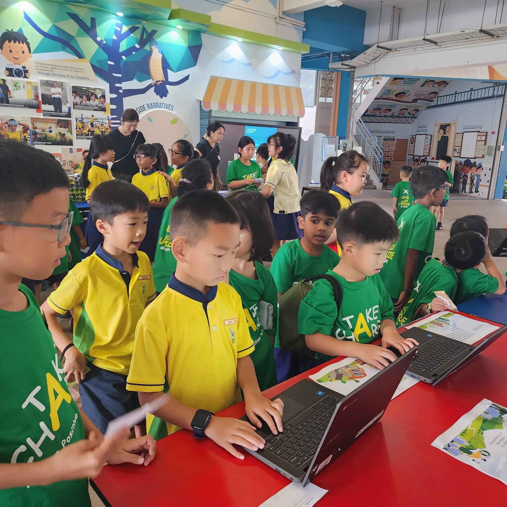 Students gather around a red table during recess to try out games designed by Green club CCA members on a laptop